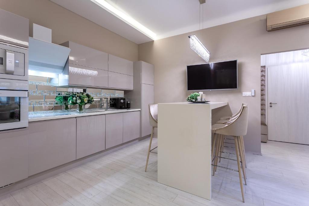 una cocina con armarios blancos y un bar con taburetes en Xen Premium Apartment, en Budapest
