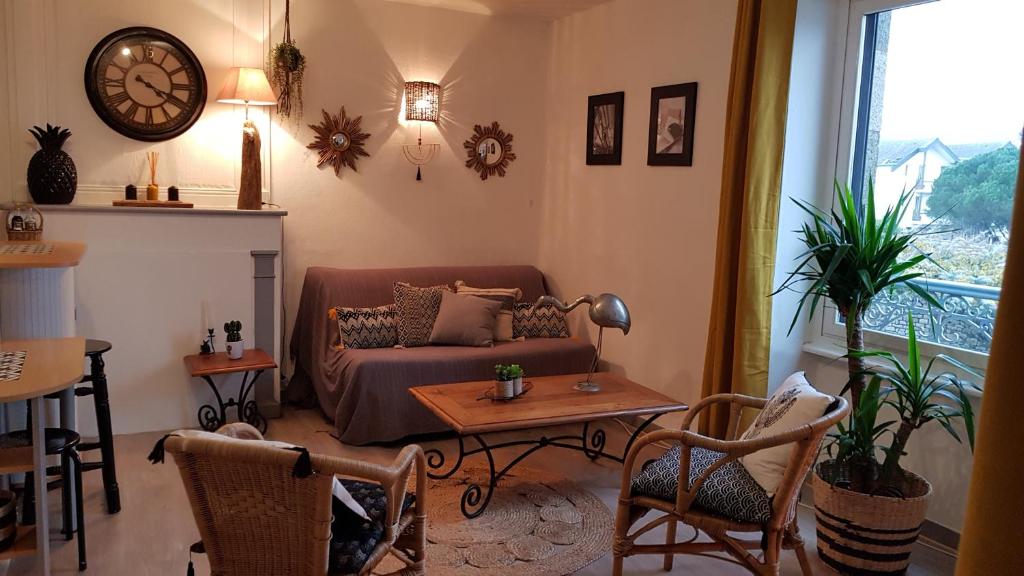 - un salon avec un canapé, une table et un réveil dans l'établissement " LA BIENVENUE ", à Ploemeur