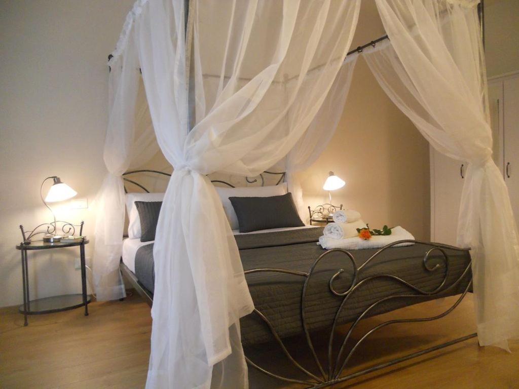 una camera con letto a baldacchino e tende bianche di Suite CALLIOPE - LE MUSE a Pietrasanta