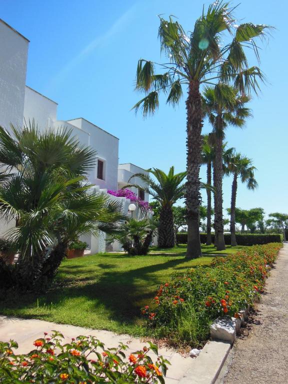 a park with palm trees and flowers and a building at Residence Club Barbara in Ostuni