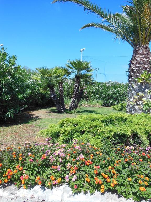 a garden with palm trees and flowers in a park at Residence Club Barbara in Ostuni