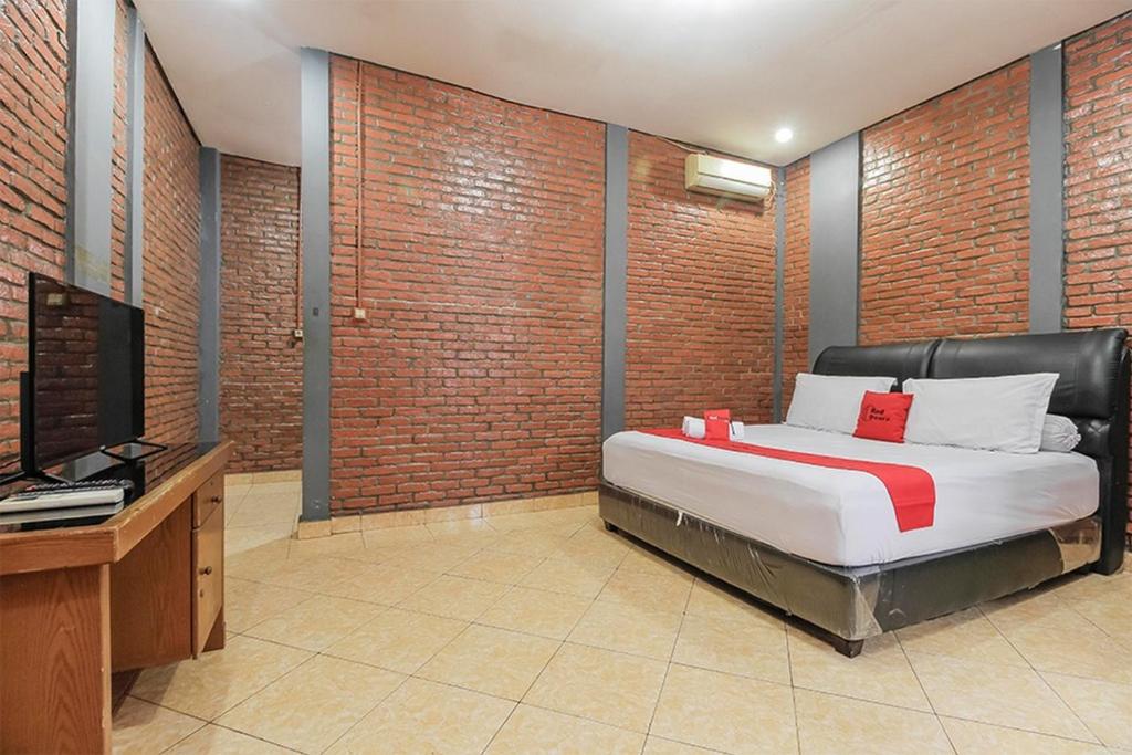 una camera con letto, scrivania e TV di RedDoorz Plus At Ampera Raya a Giacarta