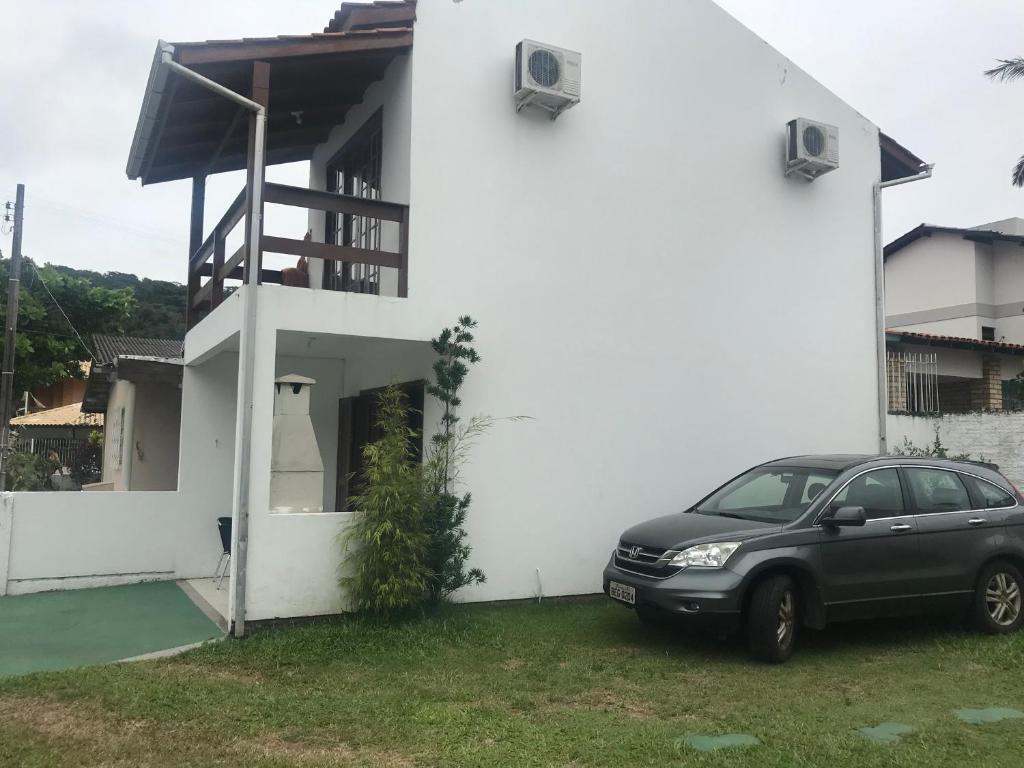 um carro estacionado em frente a uma casa branca em Sobrado,Armação -Sul da Ilha-Floripa em Florianópolis