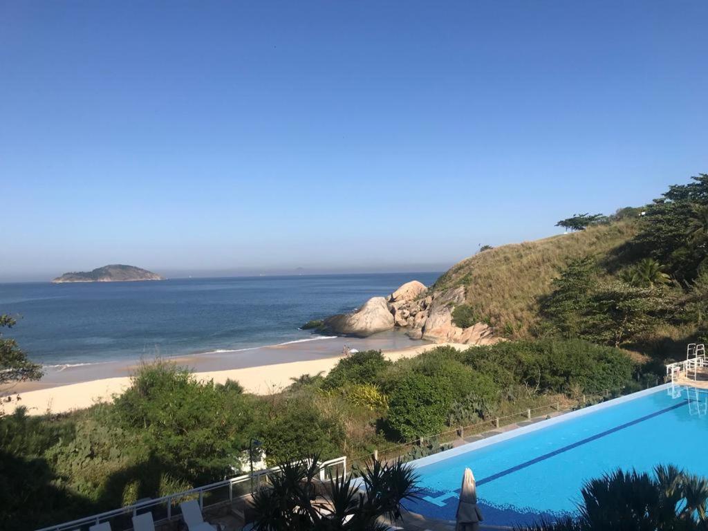a swimming pool next to a beach next to the ocean at TOTAL Mar in Niterói