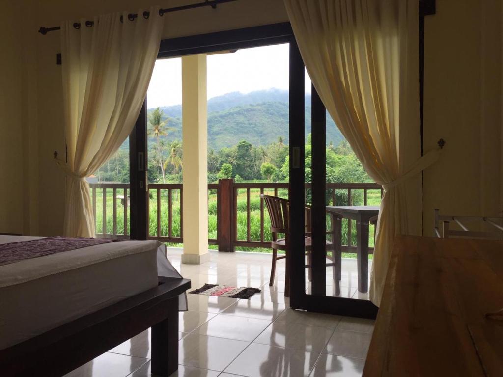 a bedroom with a bed and a balcony with a view at Tanaya Homestay in Amed