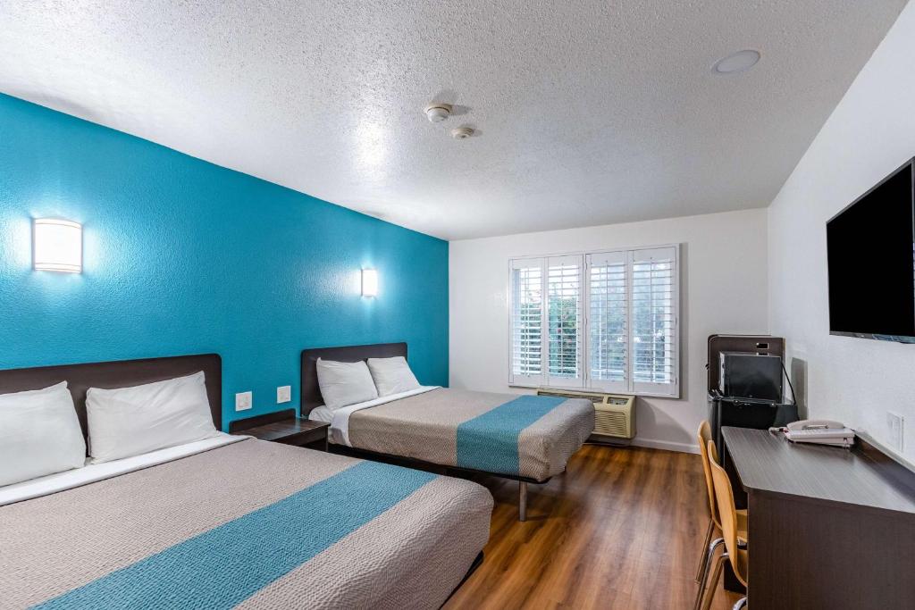 a hotel room with two beds and a blue wall at Motel 6-Fountain Valley, CA - Huntington Beach Area in Fountain Valley