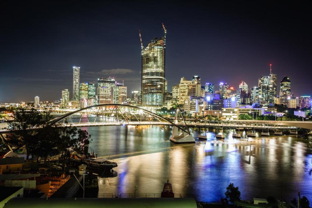 a city skyline at night with a bridge over a river at River Plaza Apartments in Brisbane