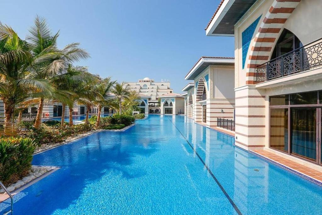 een zwembad in een villa met palmbomen bij Zabeel Saray Royal Residences Lagoon Villa in Dubai