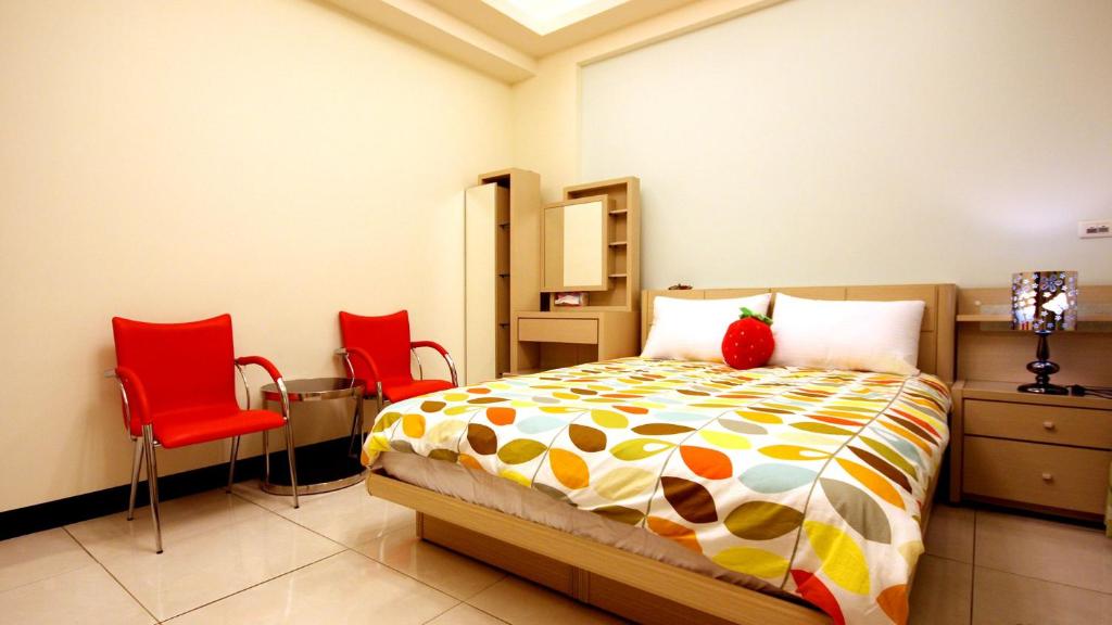 ein Schlafzimmer mit einem Bett und zwei roten Stühlen in der Unterkunft Summer House in Altstadt von Hengchun