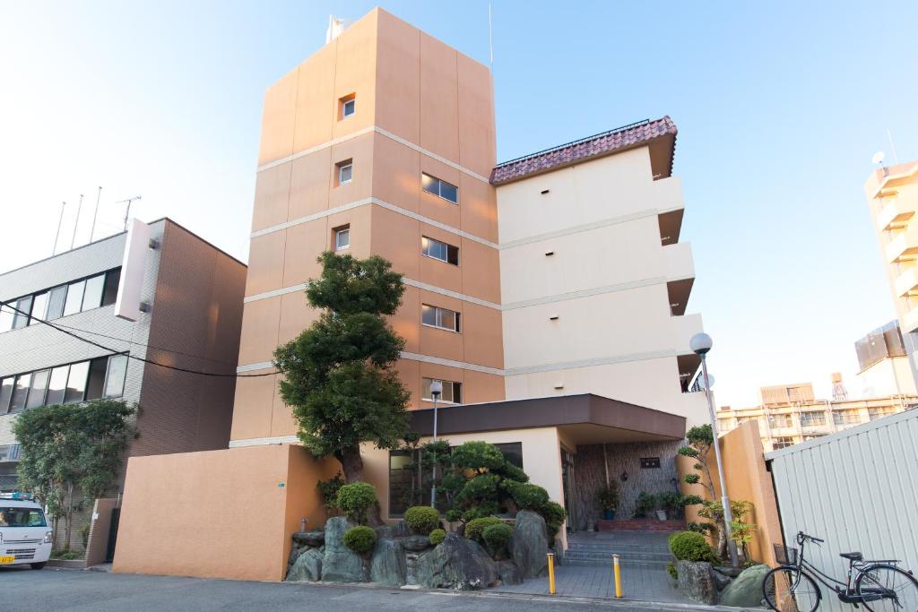 a tall building with a tree in front of it at Rose Heights -vacation rental- in Osaka