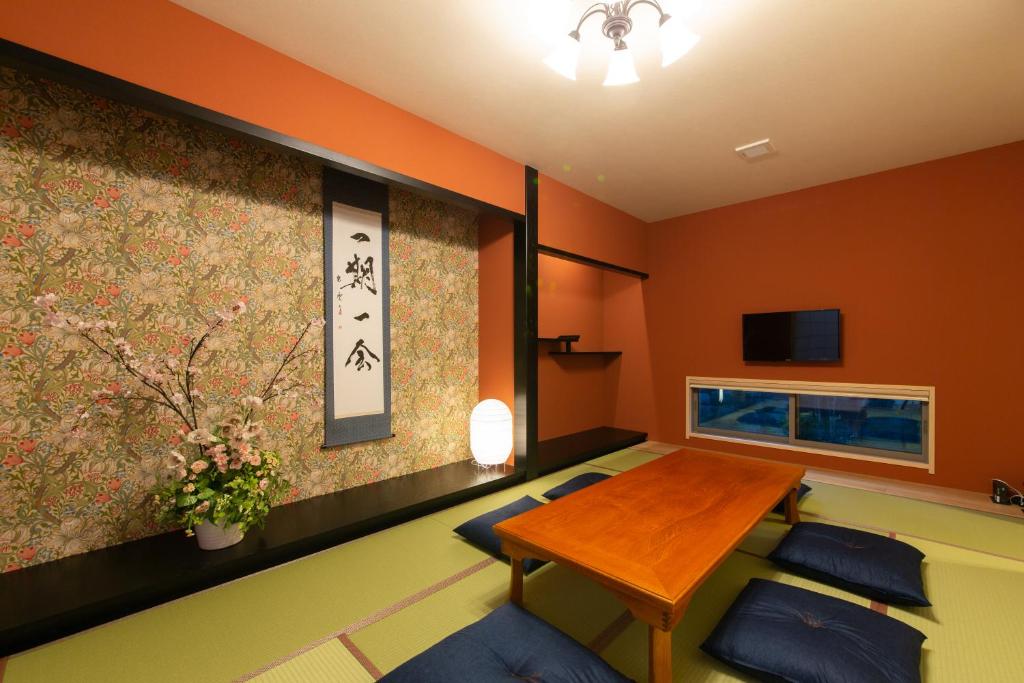 ein Wohnzimmer mit orangefarbenen Wänden sowie einem Tisch und Stühlen in der Unterkunft Yurian in Kanazawa