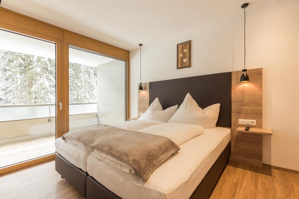 a bedroom with a large bed with a large window at Apartment Waldesruh in Oetz