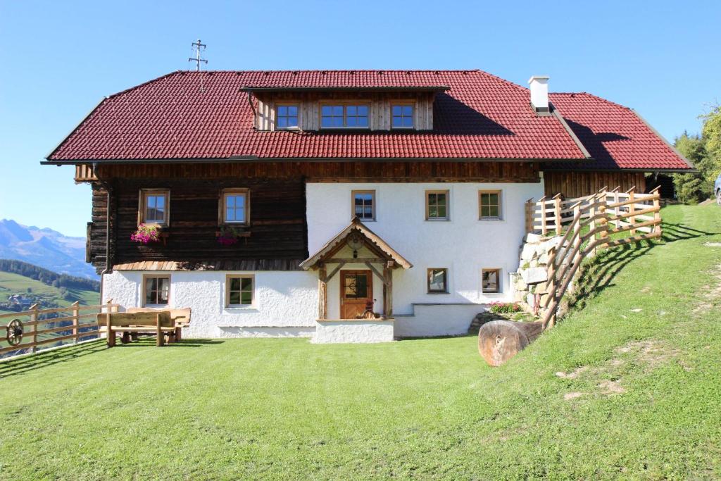ein großes Haus mit rotem Dach auf einem Hügel in der Unterkunft Lerchnerhof in Eisentratten