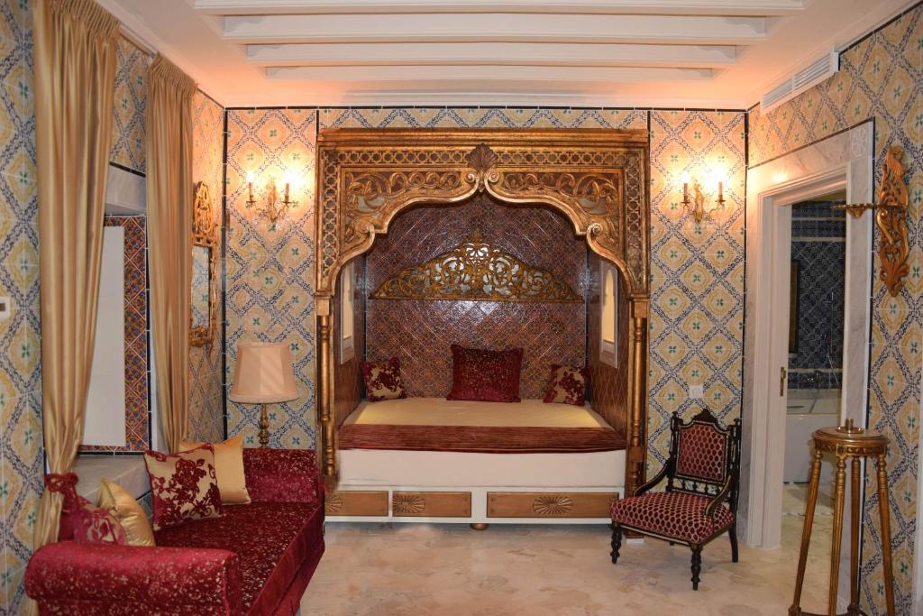 a bedroom with a bed and a chair and a couch at Dar ALOUINI in Kairouan