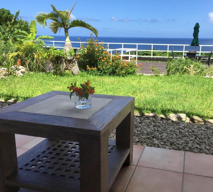Vacances a la mer Ishigaki في جزيرة إيشيغاكي: طاولة خشبية عليها إناء من الزهور