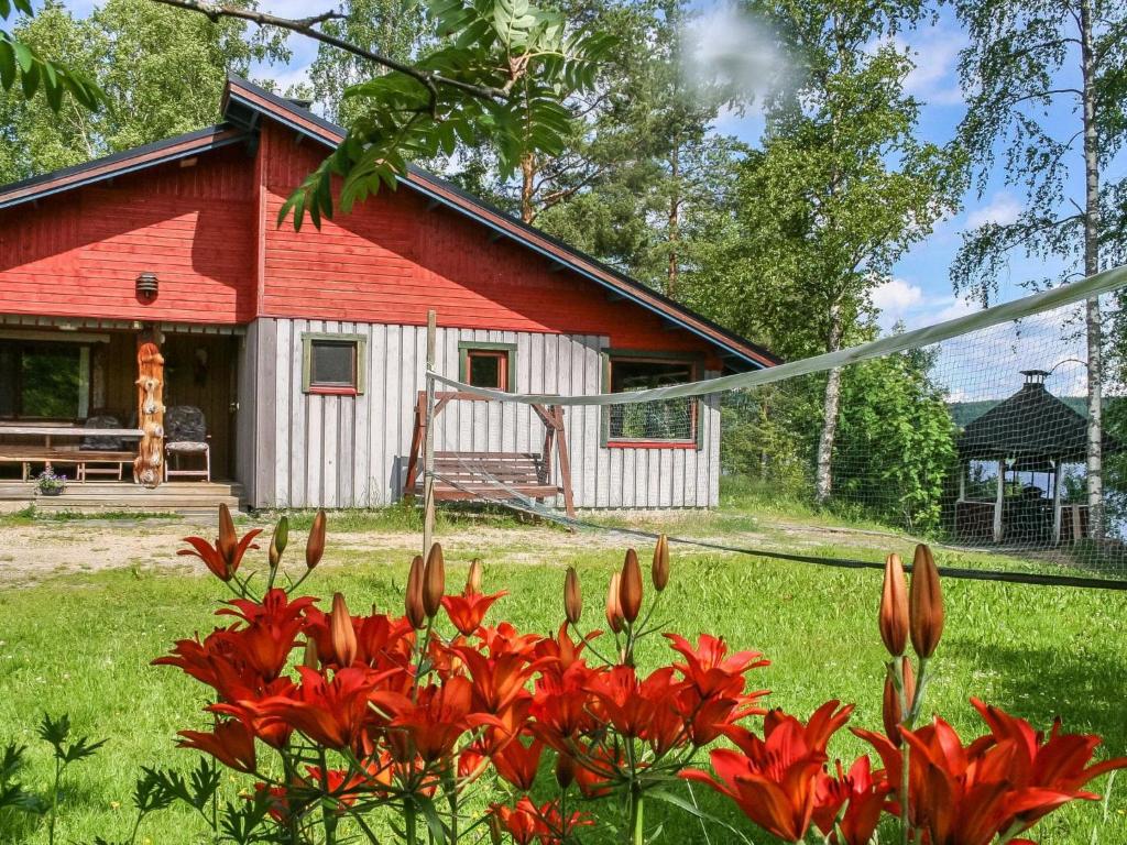 a red and white house with red flowers in the yard at Holiday Home Viehko by Interhome in Lipinlahti