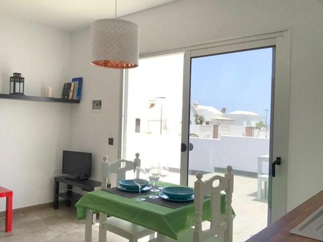 comedor con mesa verde, sillas y ventana en Sunny Studio Lanzarote, en Charco del Palo