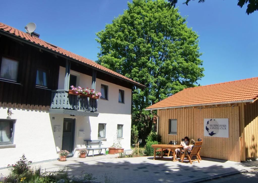 a woman sitting at a table next to a building at Pension Kainzer Sölde in Velden