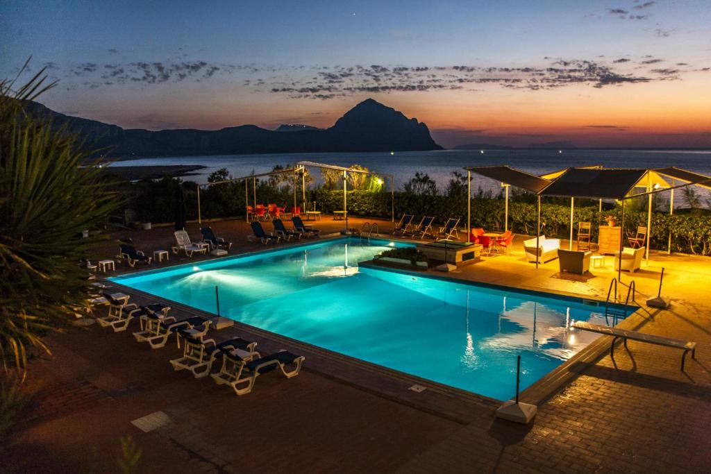 una piscina con vistas al océano por la noche en Hotel Pocho, en San Vito lo Capo