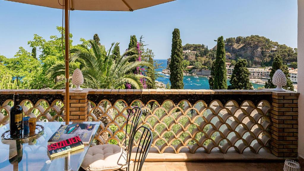 a balcony with a table and chairs and a view of the water at La Matrangela Charme Apartments in Taormina
