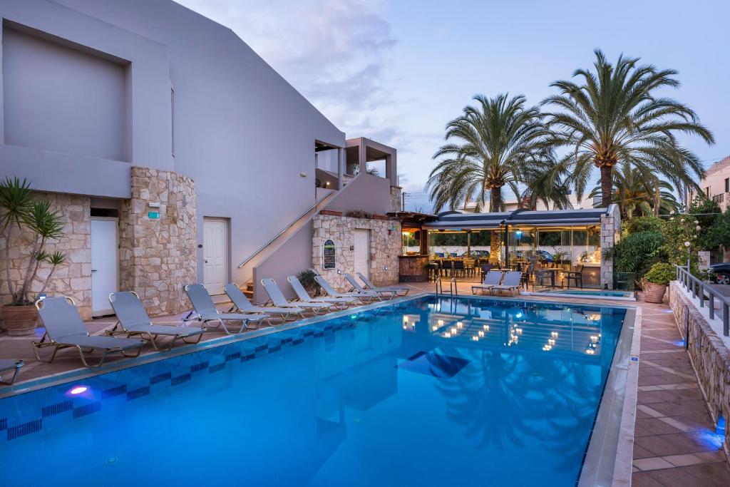 a swimming pool with chairs and a building at Elotis Suites in Agia Marina Nea Kydonias