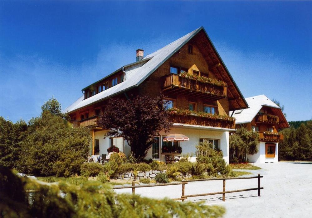 ein großes Holzhaus mit Balkon im Schnee in der Unterkunft NATURION Hotel Hinterzarten in Hinterzarten