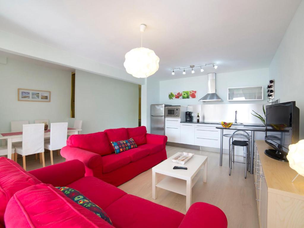 uma sala de estar com um sofá vermelho e uma cozinha em Apartment Europa I by Interhome em Calpe