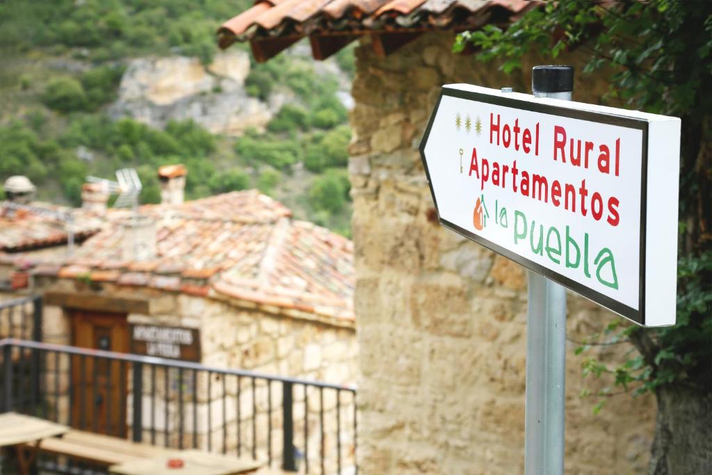 um sinal em frente a uma casa com um edifício em Hotel Rural La Puebla em Orbaneja del Castillo