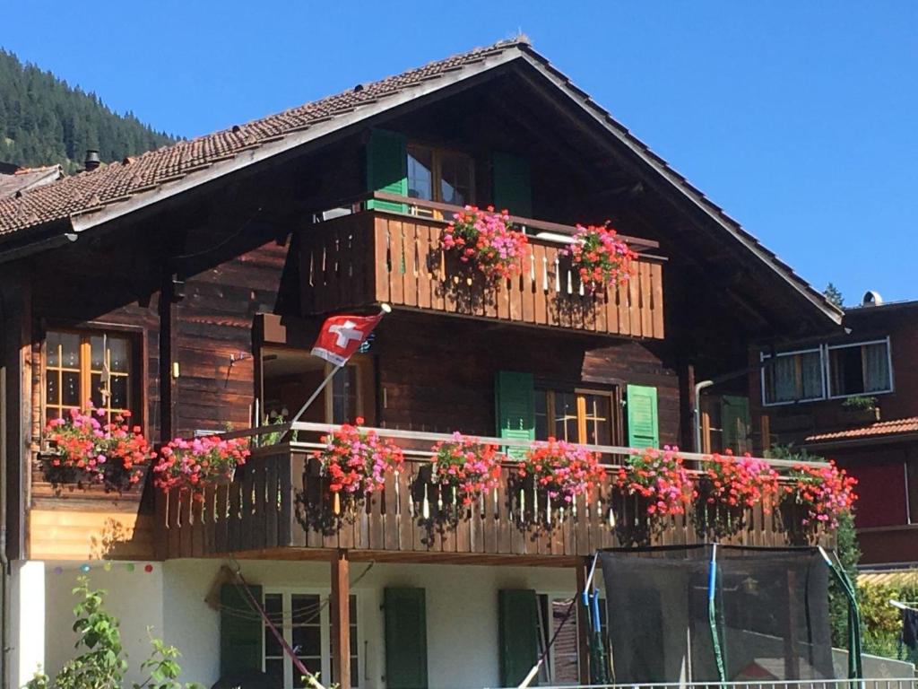 uma casa de madeira com flores na varanda em Apartment Hari by Interhome em Adelboden