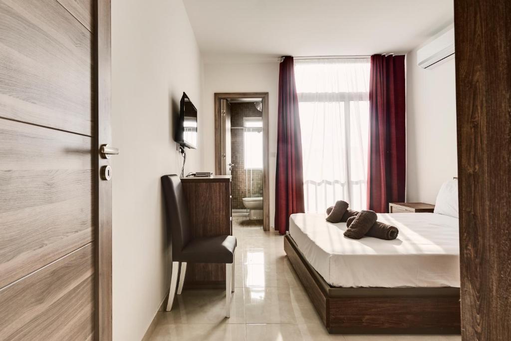 a hotel room with a bed and a chair at The Village Apartments in St Paul's Bay
