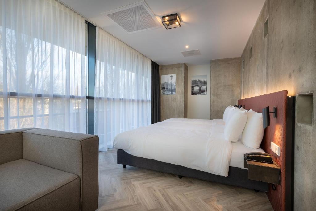 een slaapkamer met een bed, een stoel en een bank bij Hotel New Kit in Amsterdam