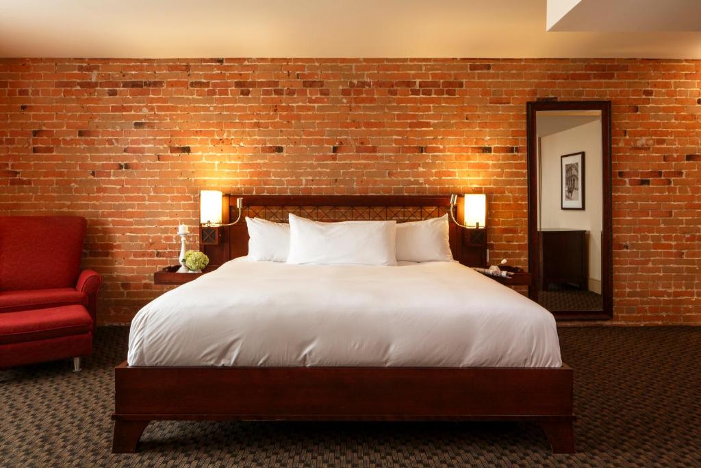 1 dormitorio con 1 cama grande y pared de ladrillo en Hotel Nelligan en Montreal