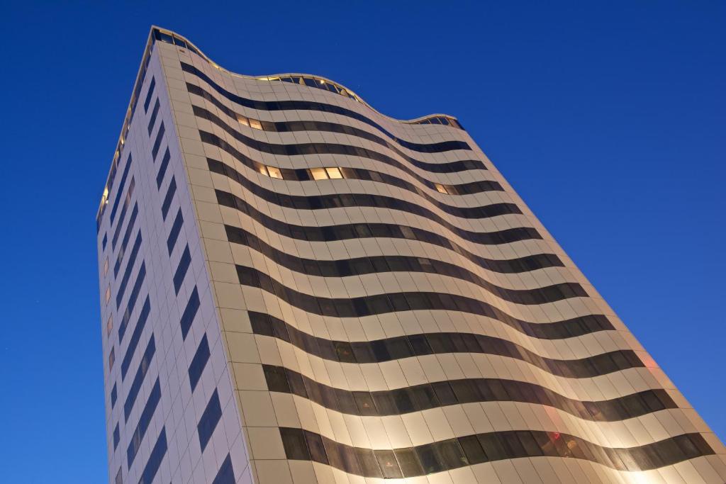 een hoog gebouw met een blauwe lucht op de achtergrond bij The Royal Riviera Hotel Doha in Doha