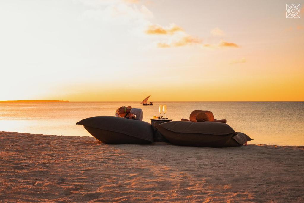two people sitting on the beach at sunset at Zuri Zanzibar in Kendwa