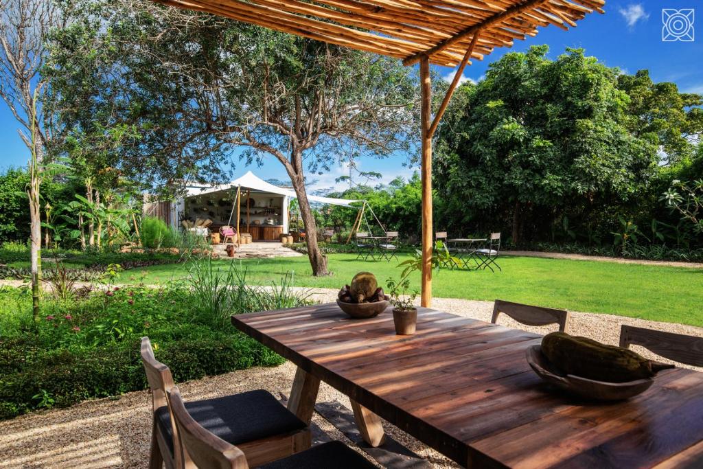 a wooden table in a garden with a tent at Zuri Zanzibar in Kendwa