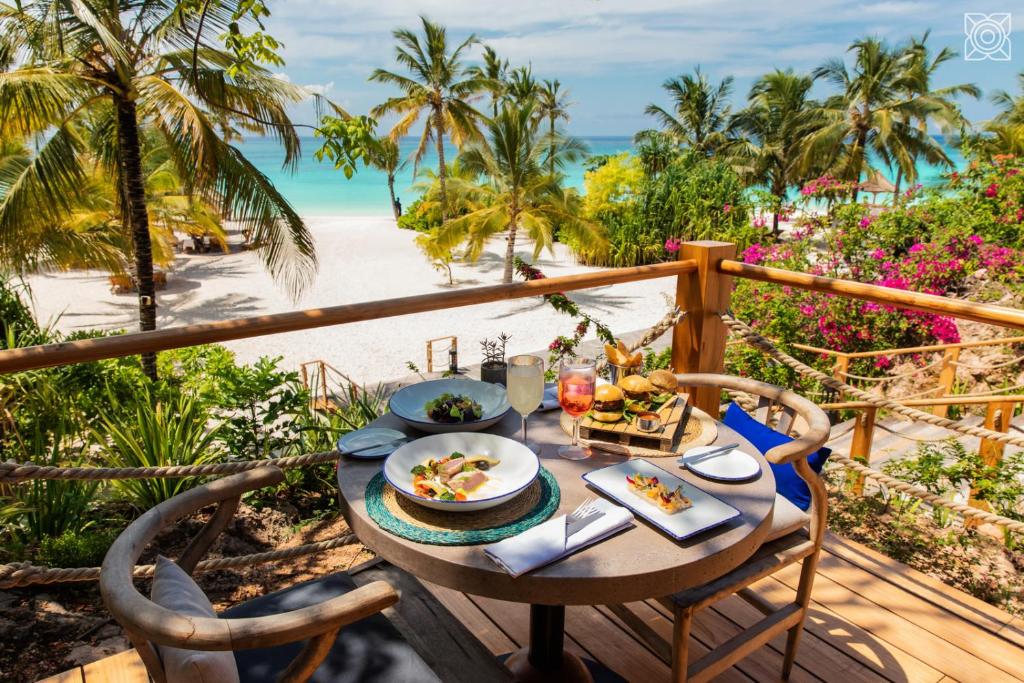 a table with food on a balcony with a view of the beach at Zuri Zanzibar in Kendwa