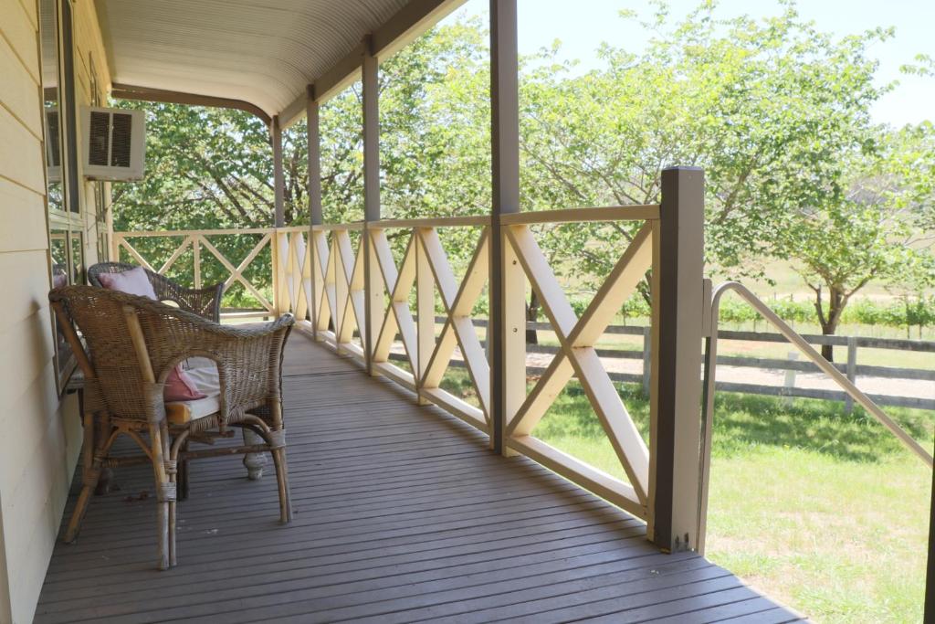 a porch with wicker chairs and a railing at Swagmans Homestead in Lidster