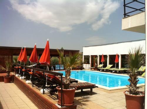 une piscine avec des chaises et des parasols rouges dans un hôtel dans l'établissement Omega Mamaia Nord, à Mamaia Nord – Năvodari