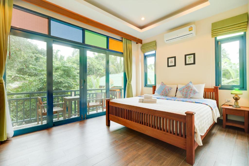 - une chambre avec un lit et un balcon avec des fenêtres dans l'établissement Baan Patcharintorn Samui, à Chaweng