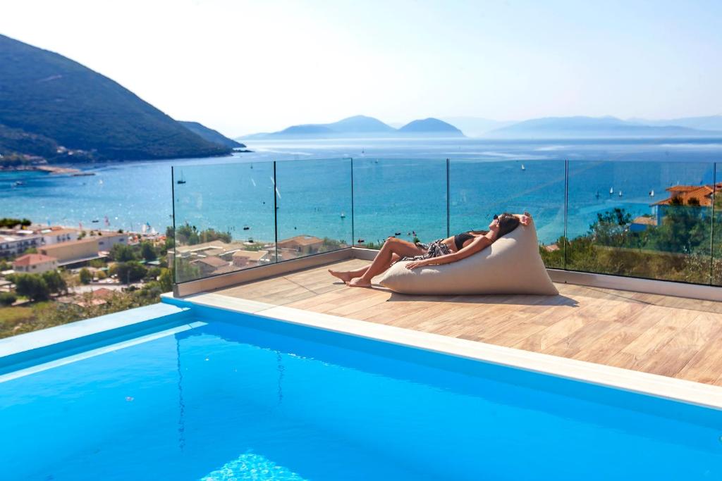 a woman laying on a chair next to a swimming pool at Drakatos Villas in Vasiliki