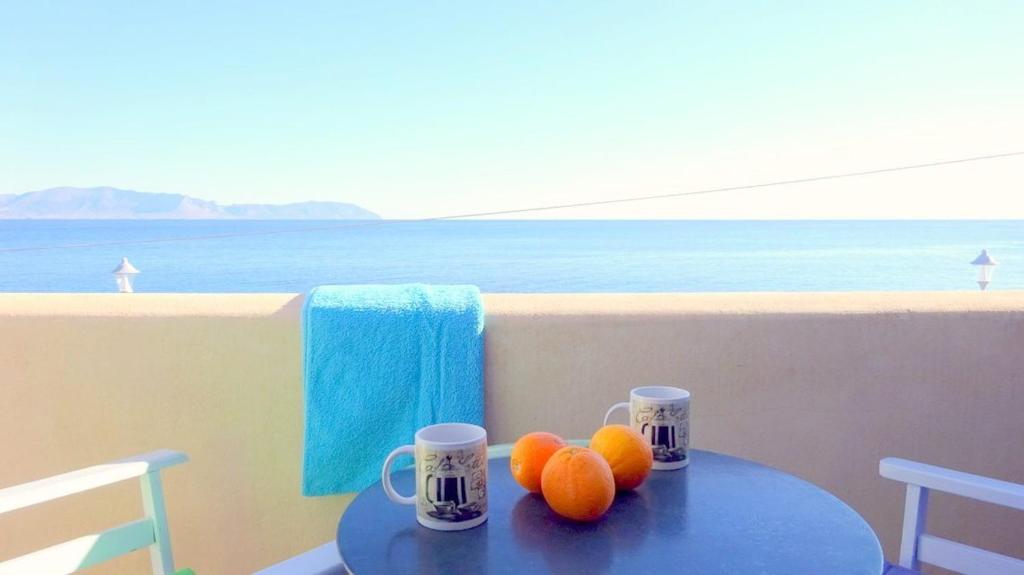 una mesa con naranjas en ella con dos tazas en ella en ARETOUSA, en Agia Pelagia - Citera