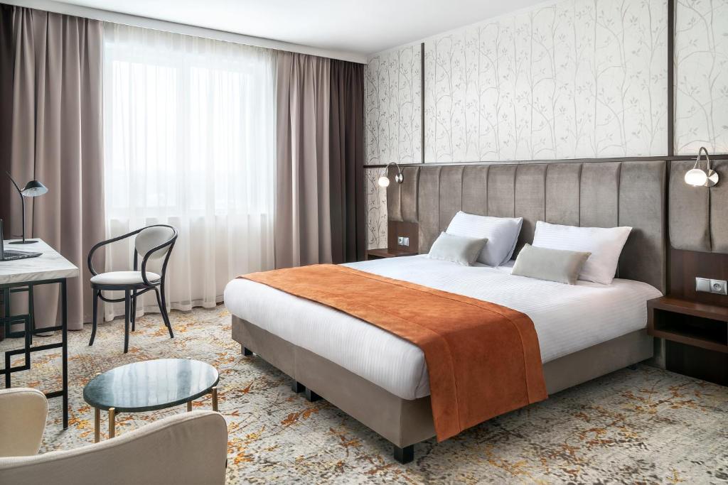 a hotel room with a bed and a desk at Metropolo by Golden Tulip Krakow in Krakow