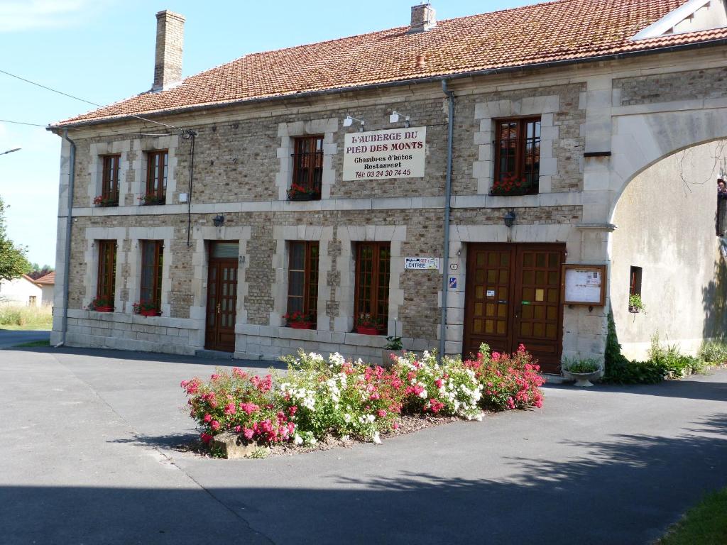 Grivy-Loisy的住宿－auberge du pied des monts，一座古老的石头建筑,前面有鲜花