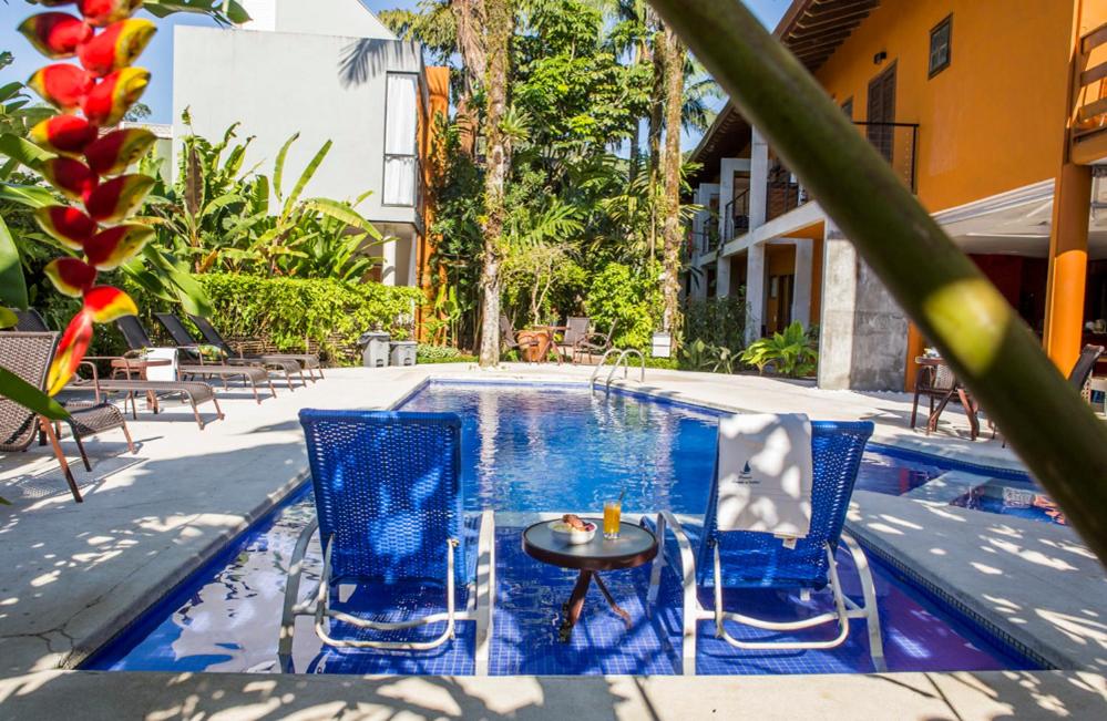 a pool with two blue chairs and a table and a table at Pousada Armação de Camburi in Camburi