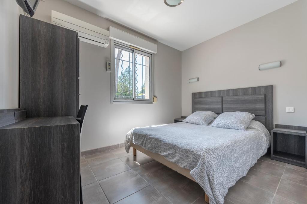 1 dormitorio con cama, ventana y TV en Hôtel du Rocher, en Marsella