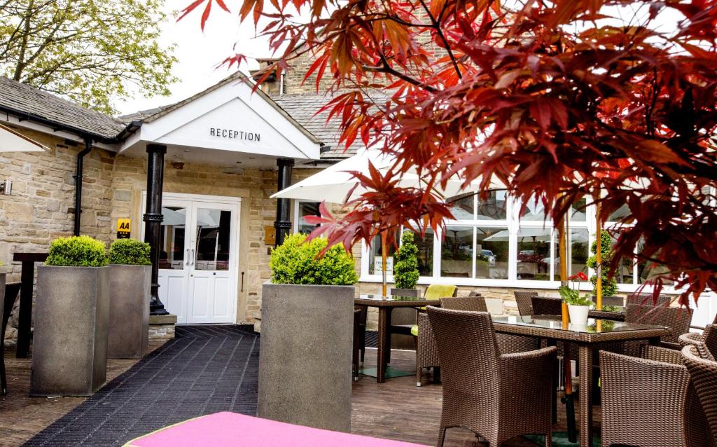 eine Terrasse mit Tischen und Stühlen vor einem Gebäude in der Unterkunft Herriots Hotel in Skipton