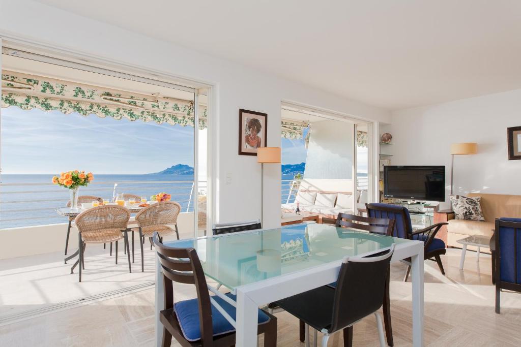 a dining room and living room with a glass table and chairs at Mer du Sud 4 YourHostHelper in Cannes