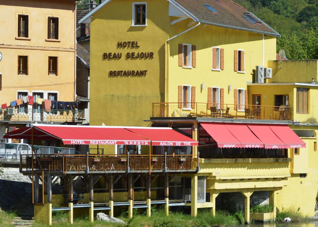 un edificio con un restaurante con techo rojo en Hôtel Au Fil de L'Eau en Seyssel