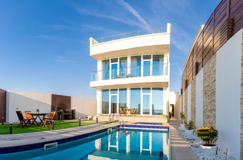 une maison avec une piscine en face d'une maison dans l'établissement Sunrise Villas, à Al Sharqiyah