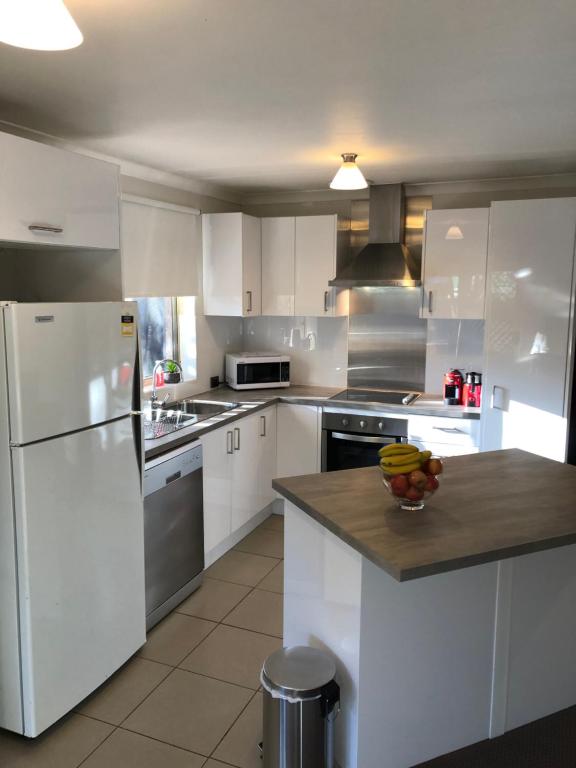 a kitchen with white appliances and a bowl of fruit on a counter at 5A Glenelg Street in Perth